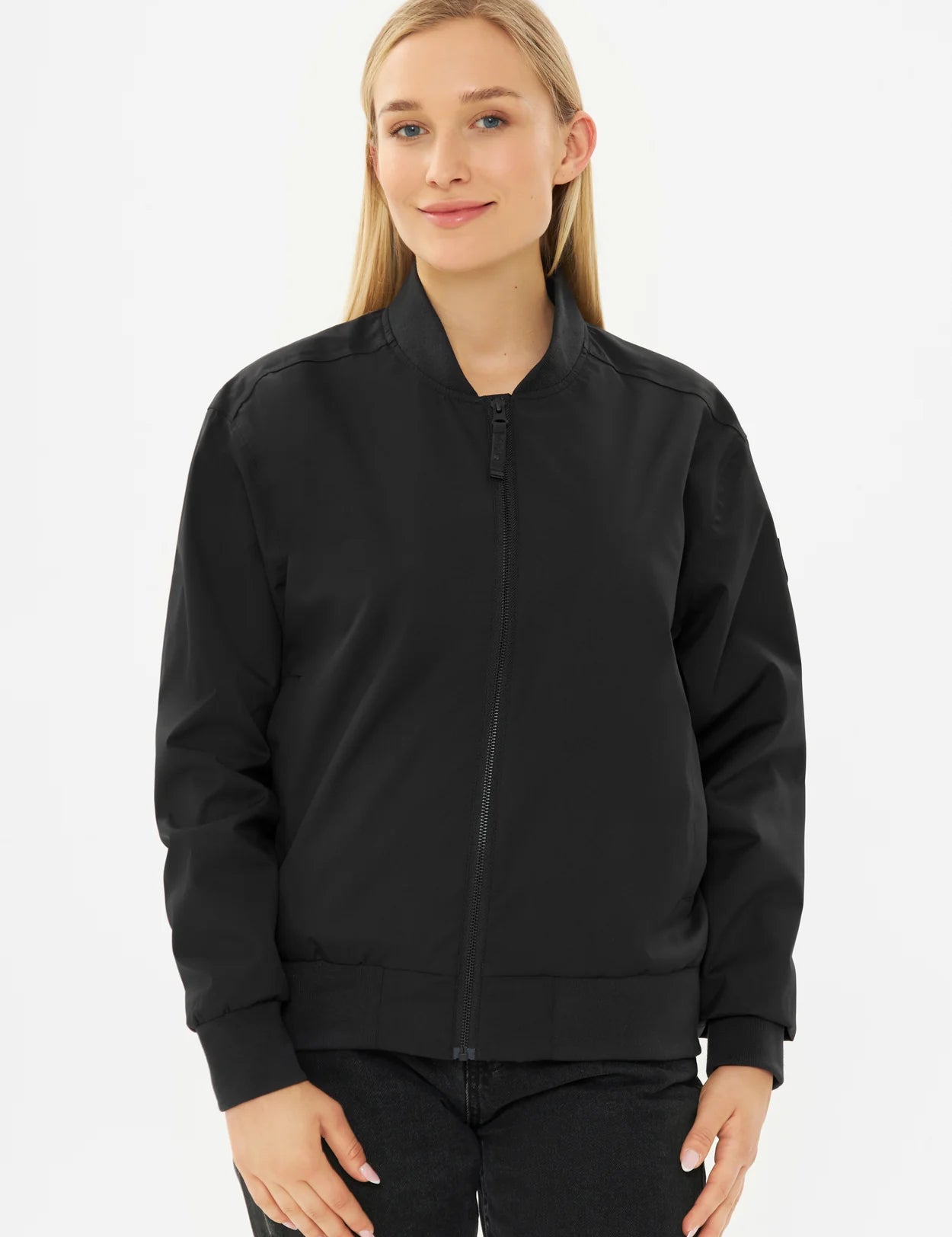 Frau in schwarzer Bomberjacke und Jeans.
