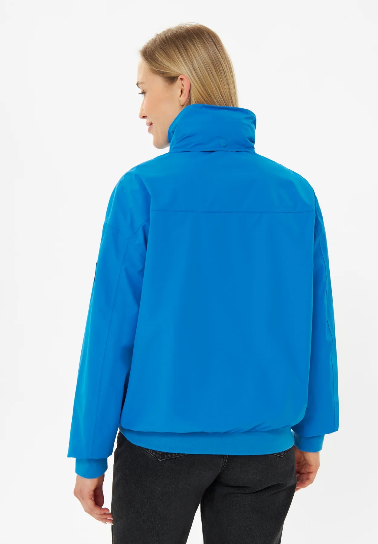 Frau trägt blaue Outdoorjacke, Rückansicht.