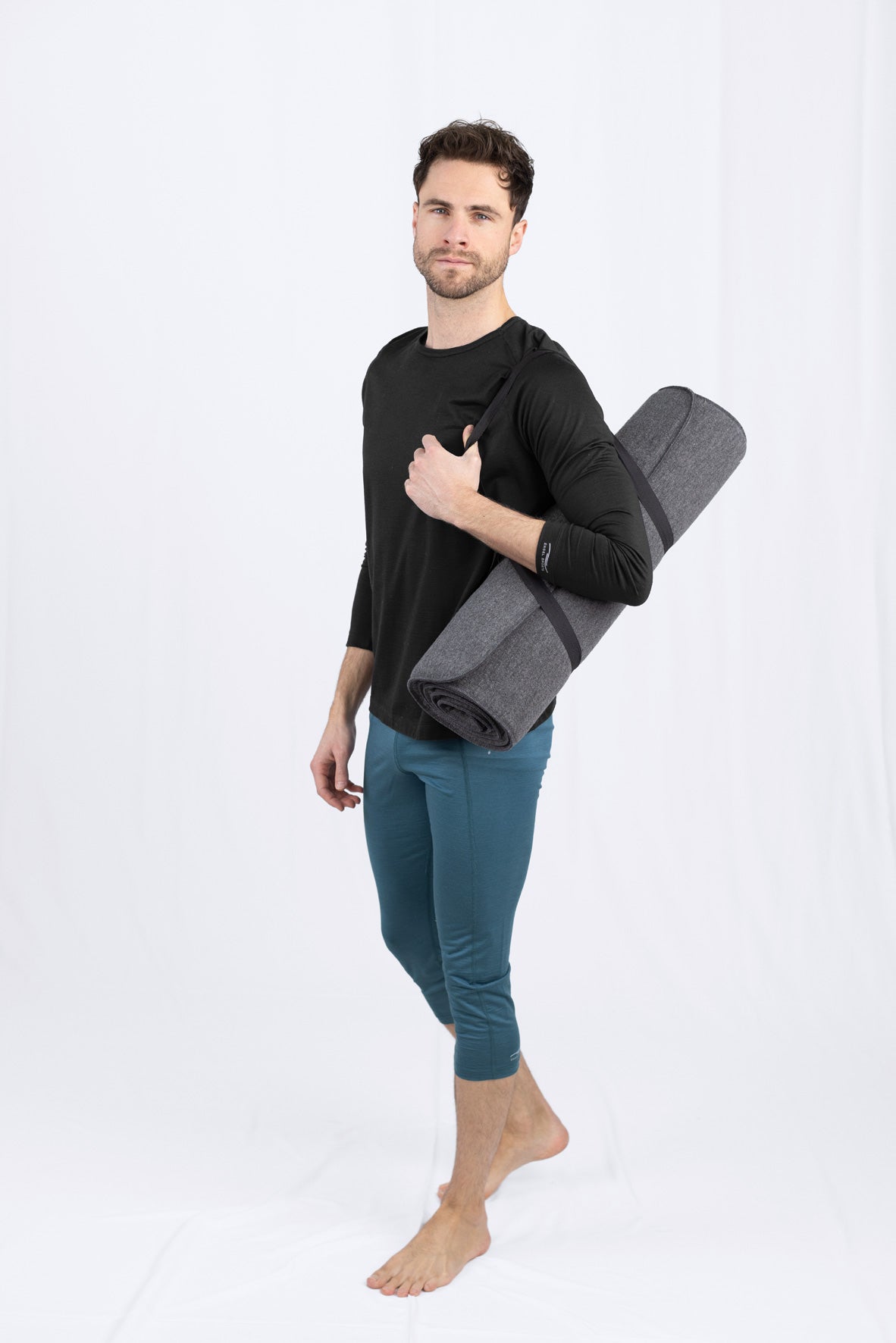 Mann mit Yogamatte posiert im Studio