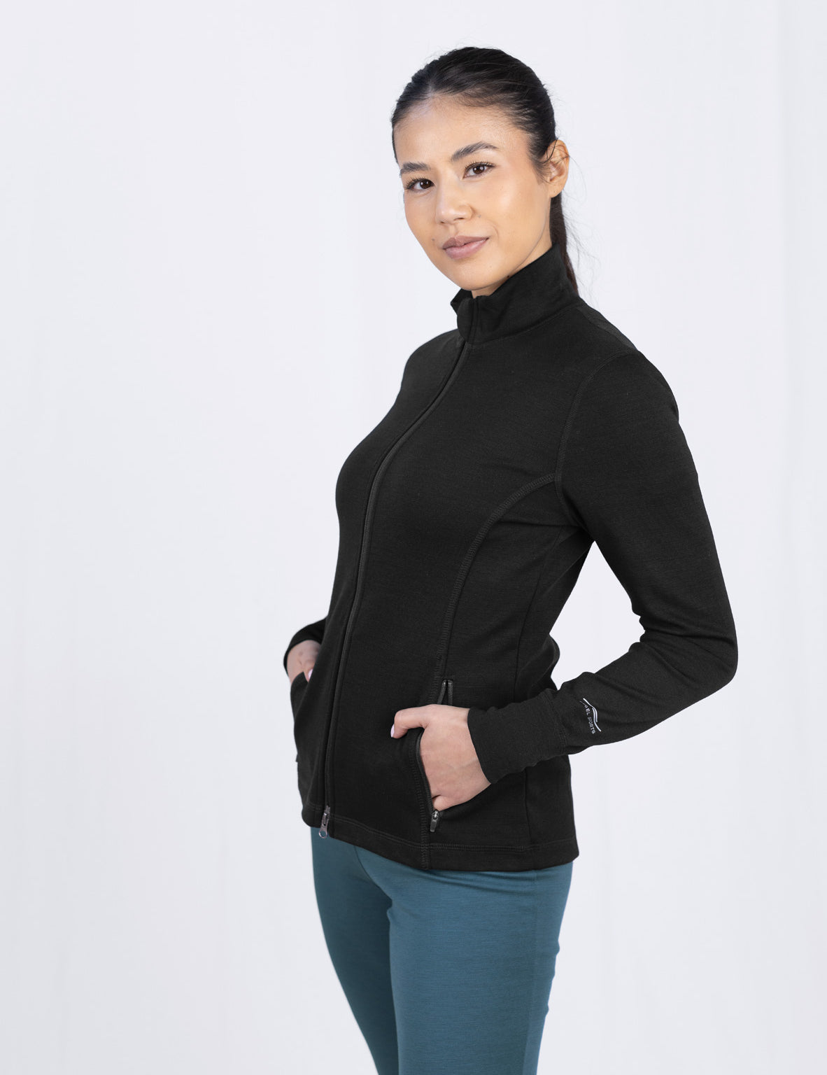 Frau in schwarzer Jacke und türkisen Hosen