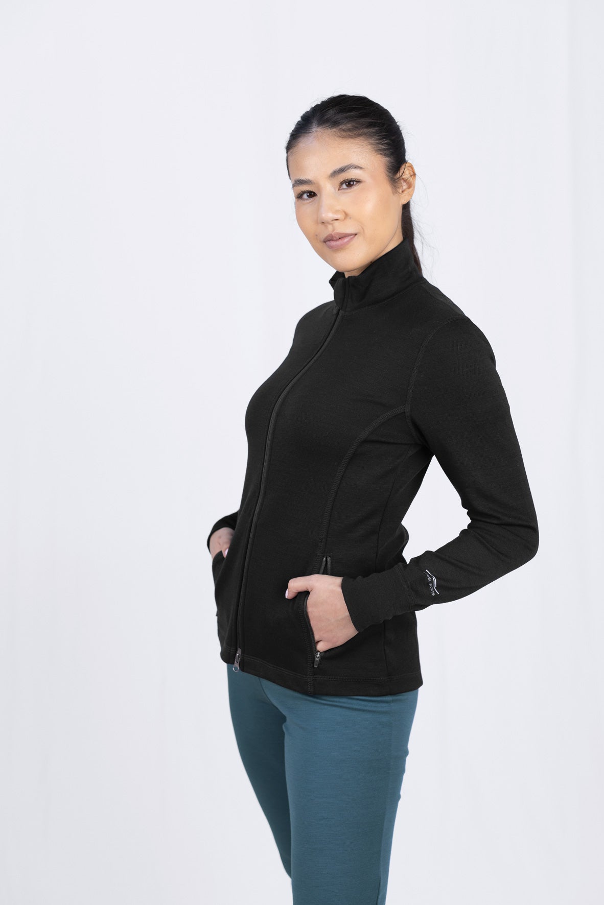 Frau in schwarzer Jacke und türkisen Hosen