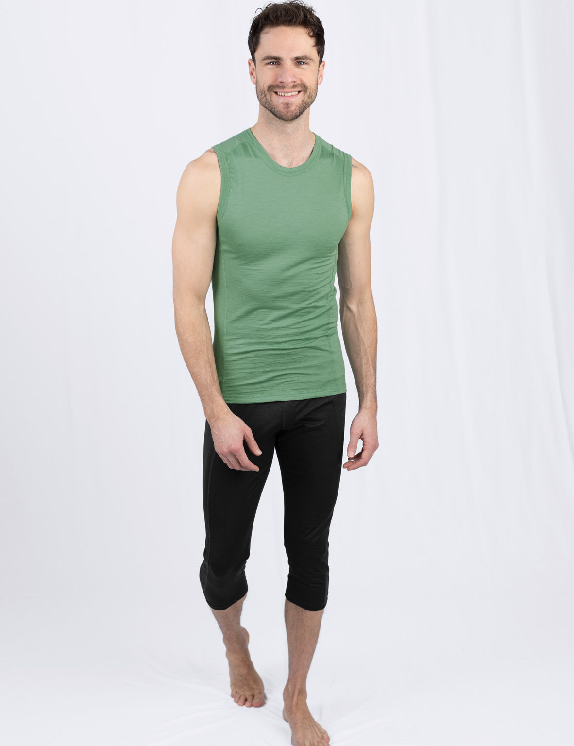 Lächelnder Mann in grünem Tanktop und schwarzer Hose