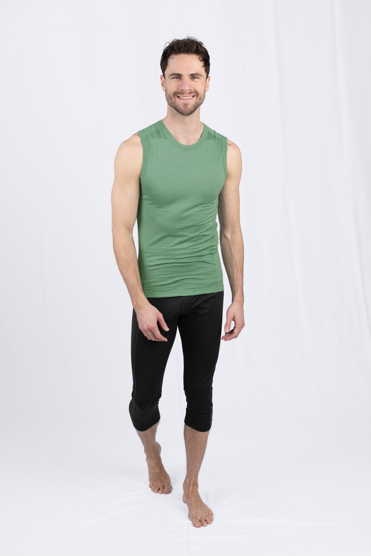Lächelnder Mann in grünem Tanktop und schwarzer Hose