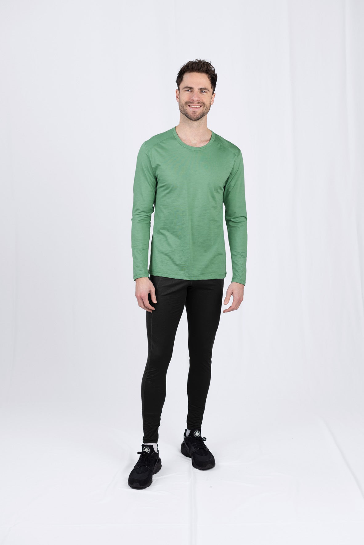 Lächelnder Mann in grünem Shirt und schwarzen Leggings