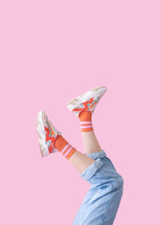 Beine in Turnschuhen vor rosa Hintergrund.