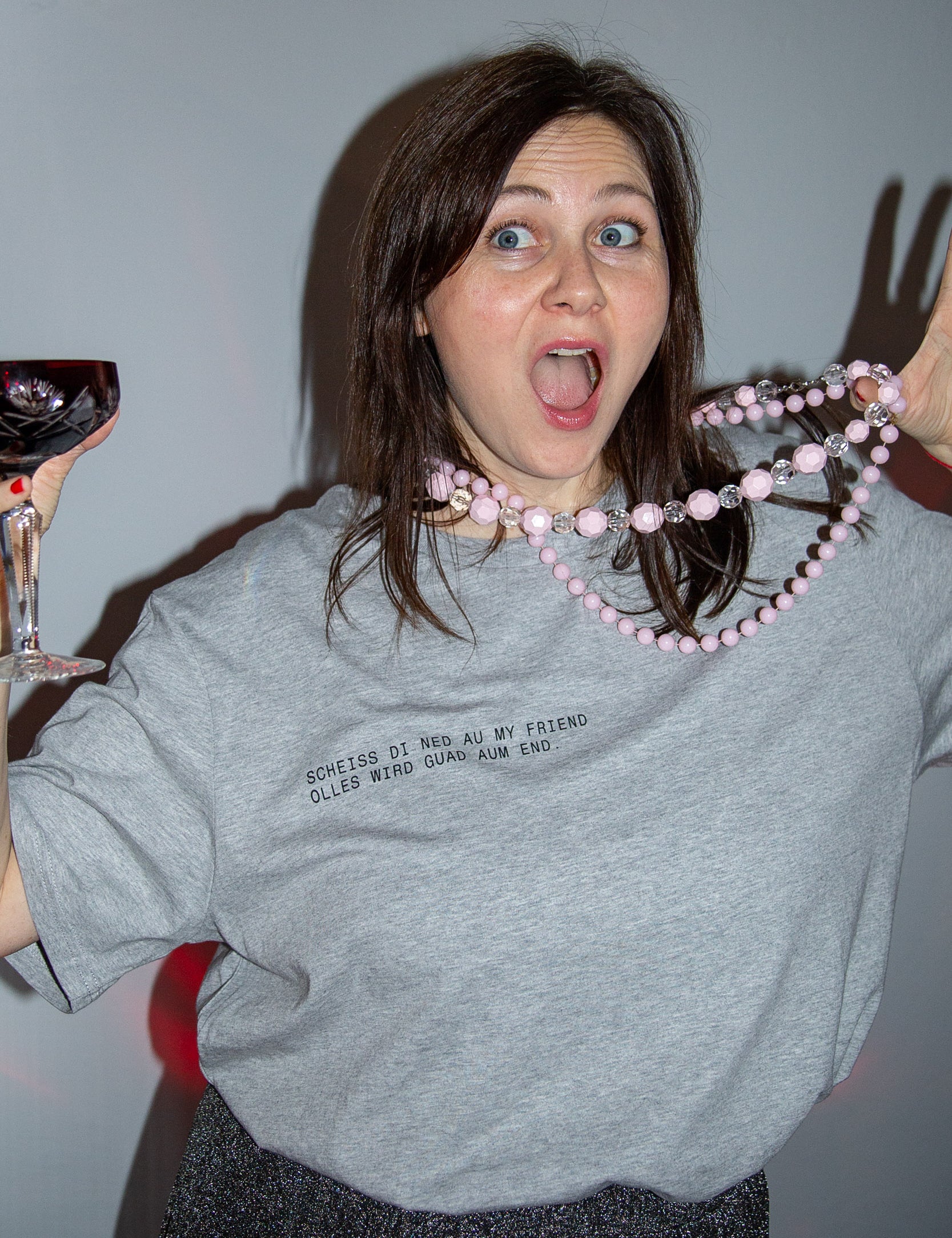 Überraschte Frau mit Wein und Perlenkette