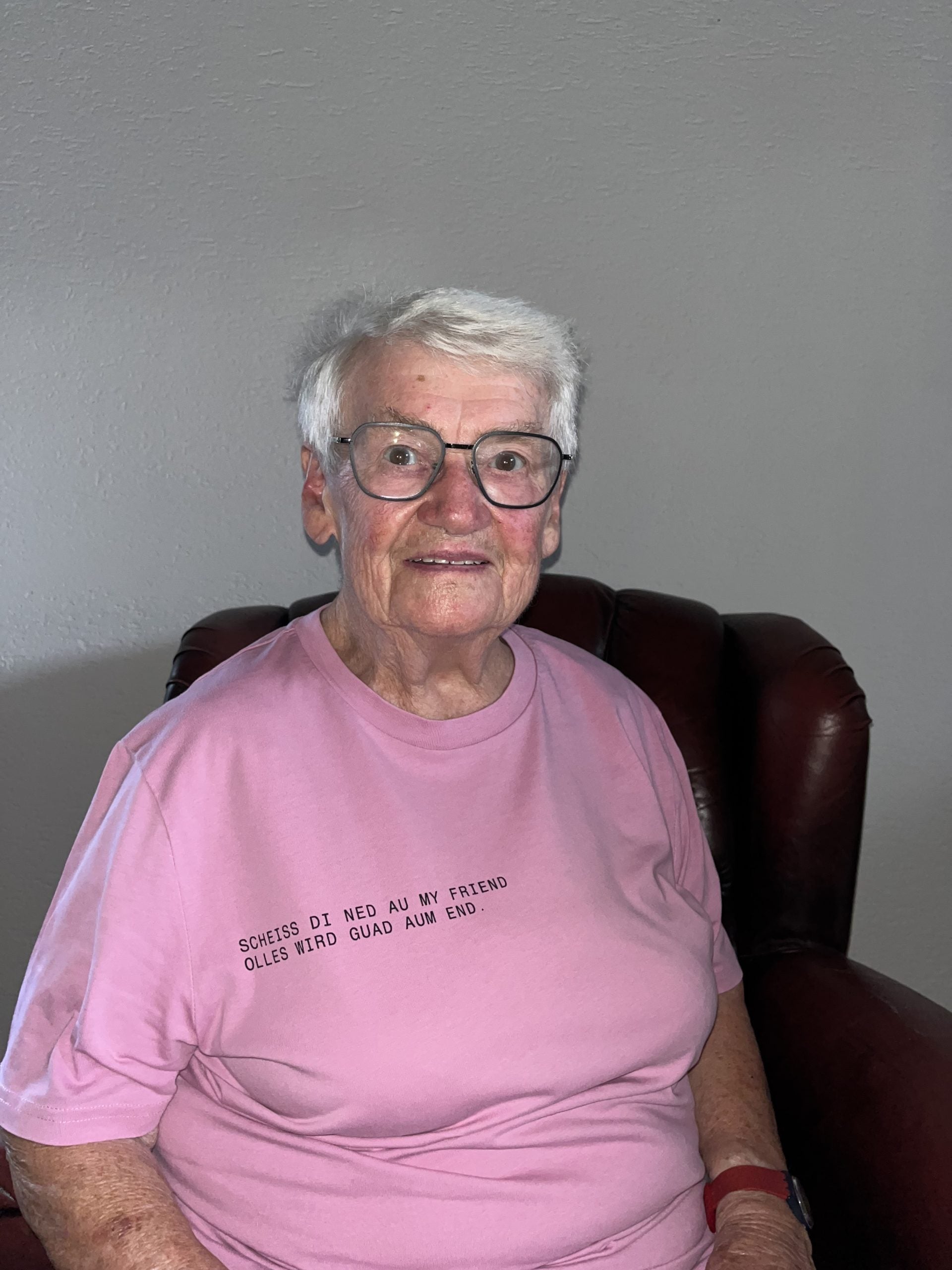 Ältere Frau lächelt in rosafarbenem T-Shirt