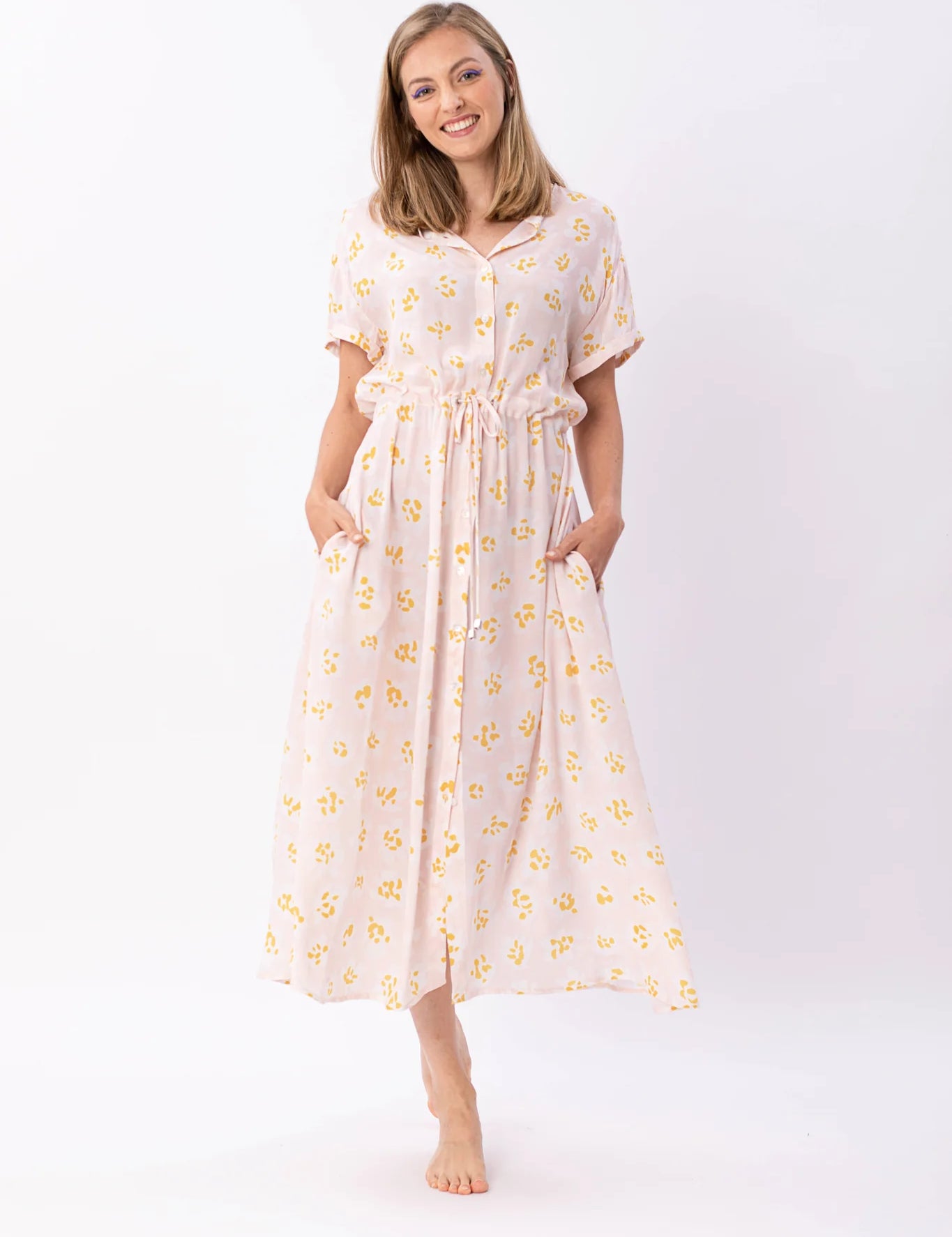 Frau in gelbem Blumenkleid lächelt freundlich.