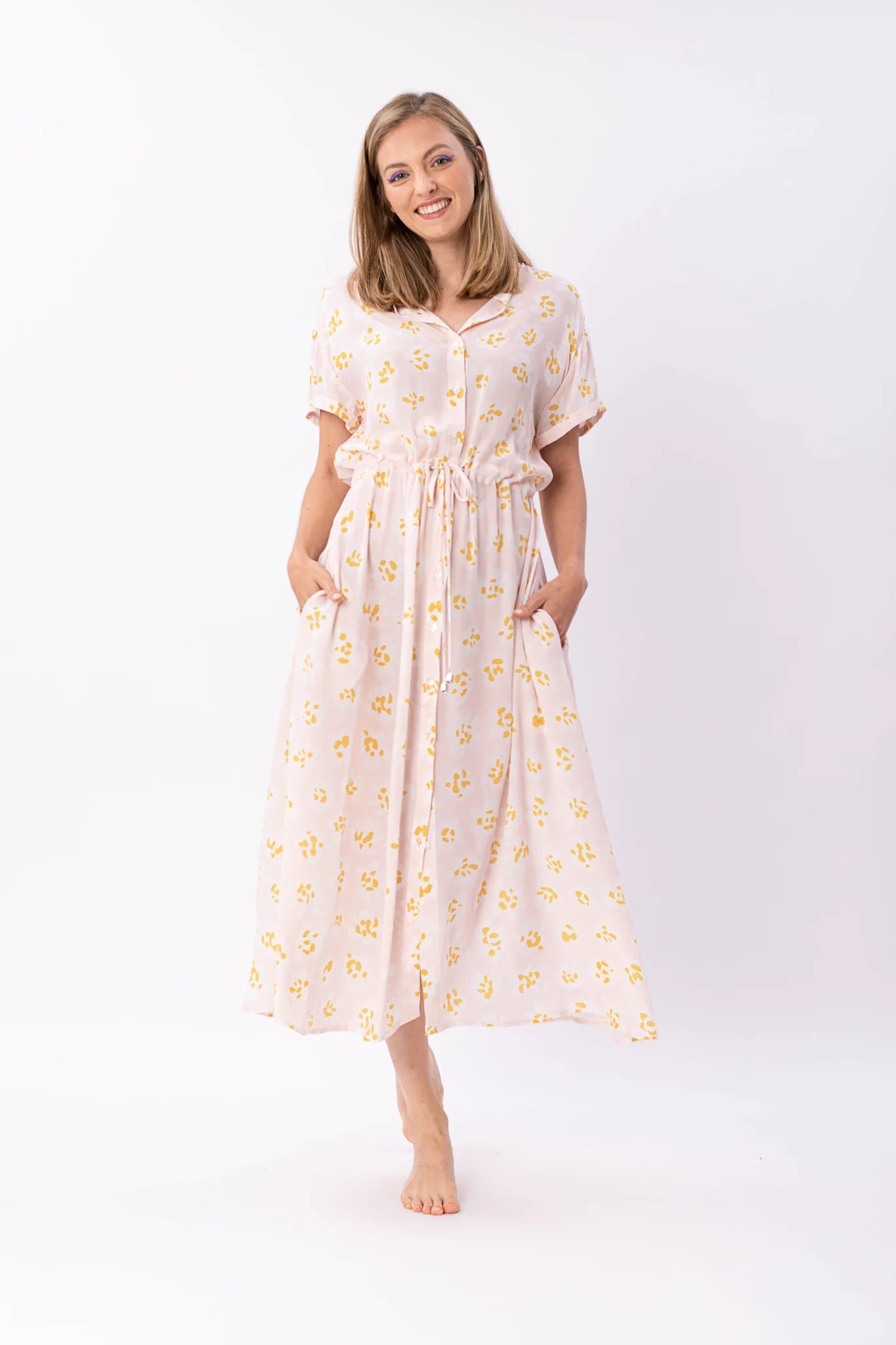 Frau in gelbem Blumenkleid lächelt freundlich.