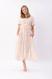 Frau in gelbem Blumenkleid lächelt freundlich.