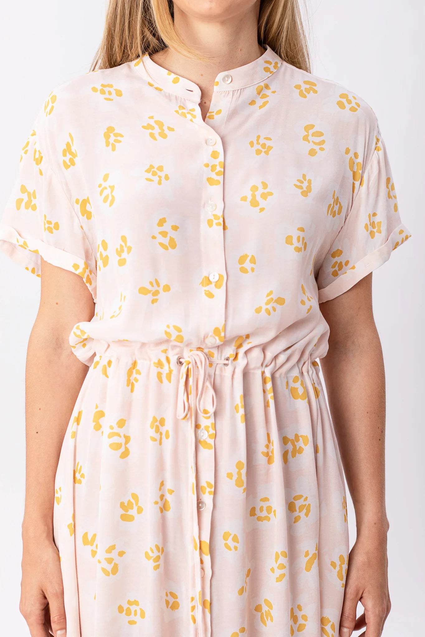 Frau trägt rosa Kleid mit gelben Blumenmustern.
