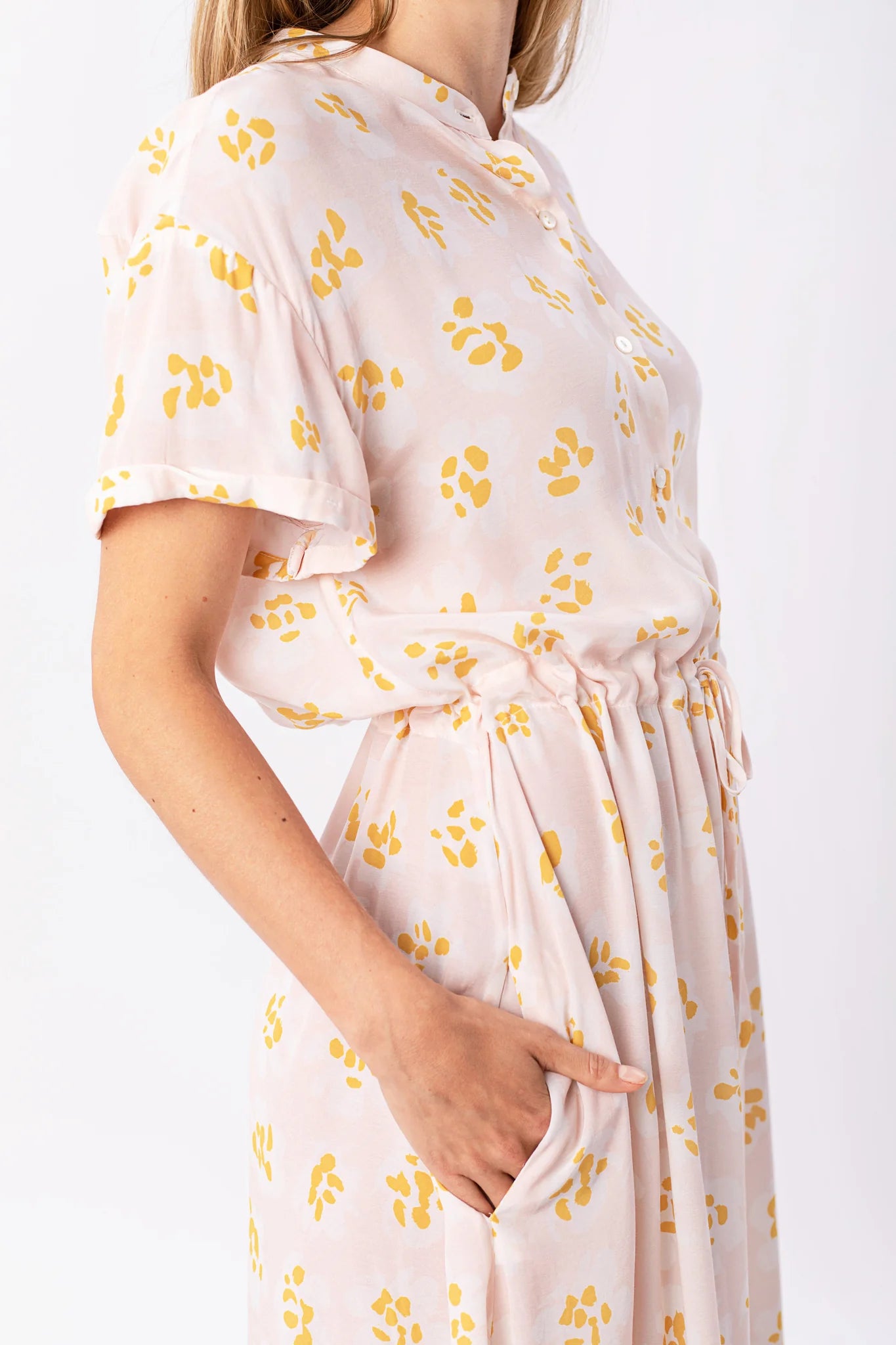Frau im rosafarbenen Kleid mit gelben Blumenmustern.