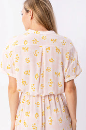 Frau in rosa Kleid mit gelben Blumenmuster.
