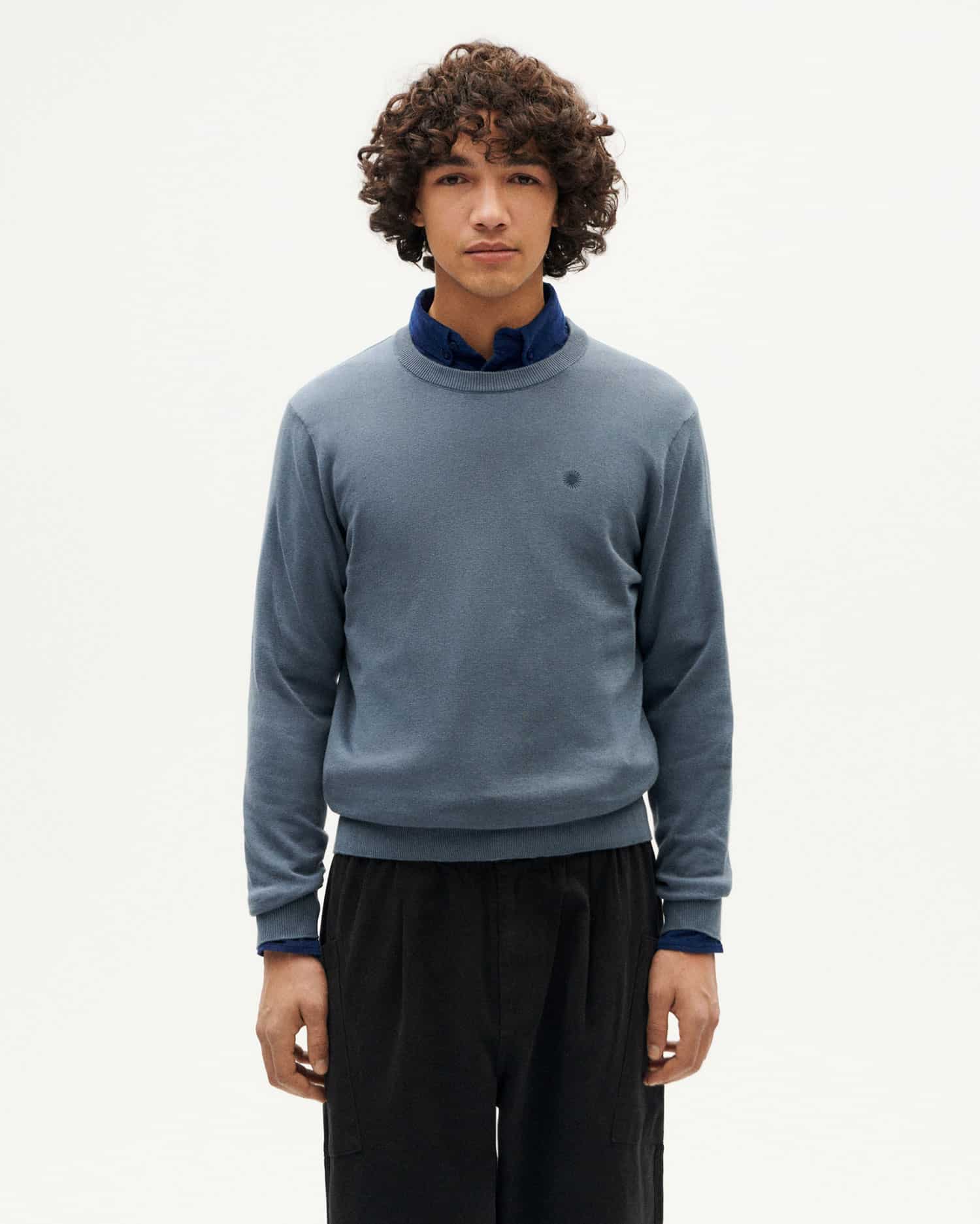 Junger Mann in blauem Pullover und schwarzer Hose