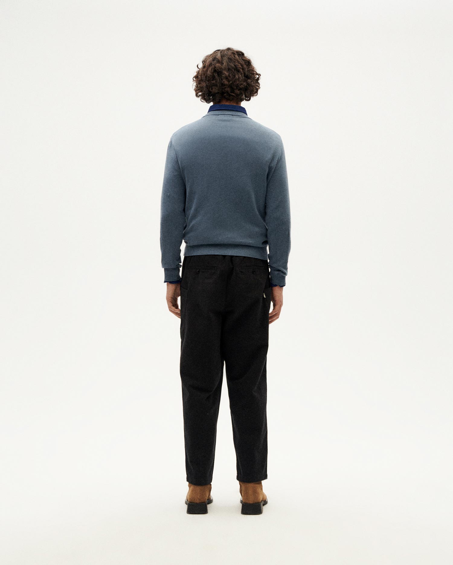 Mann von hinten in blauer Strickjacke und schwarzer Hose