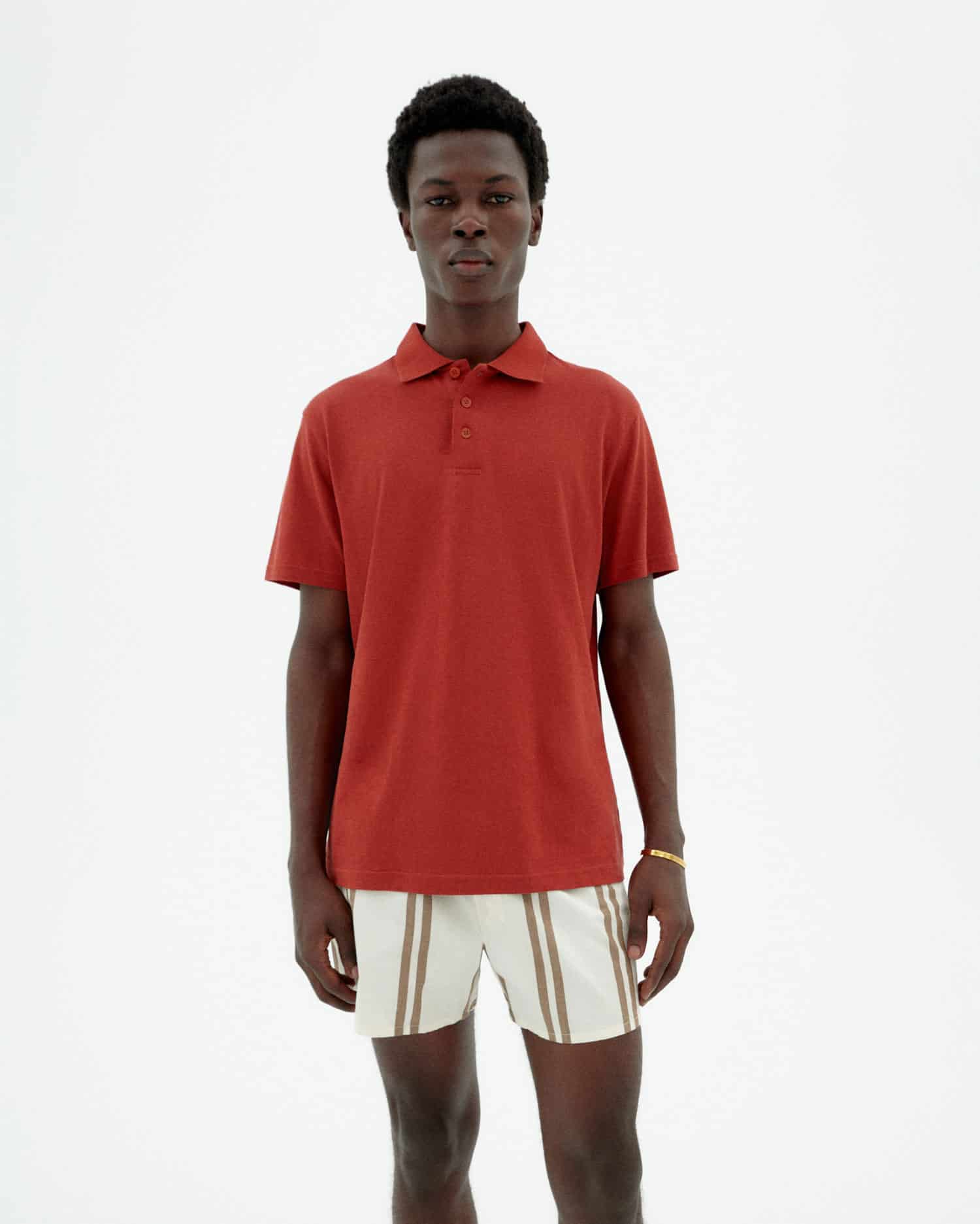 Junger Mann trägt rotes Poloshirt und weiße Shorts
