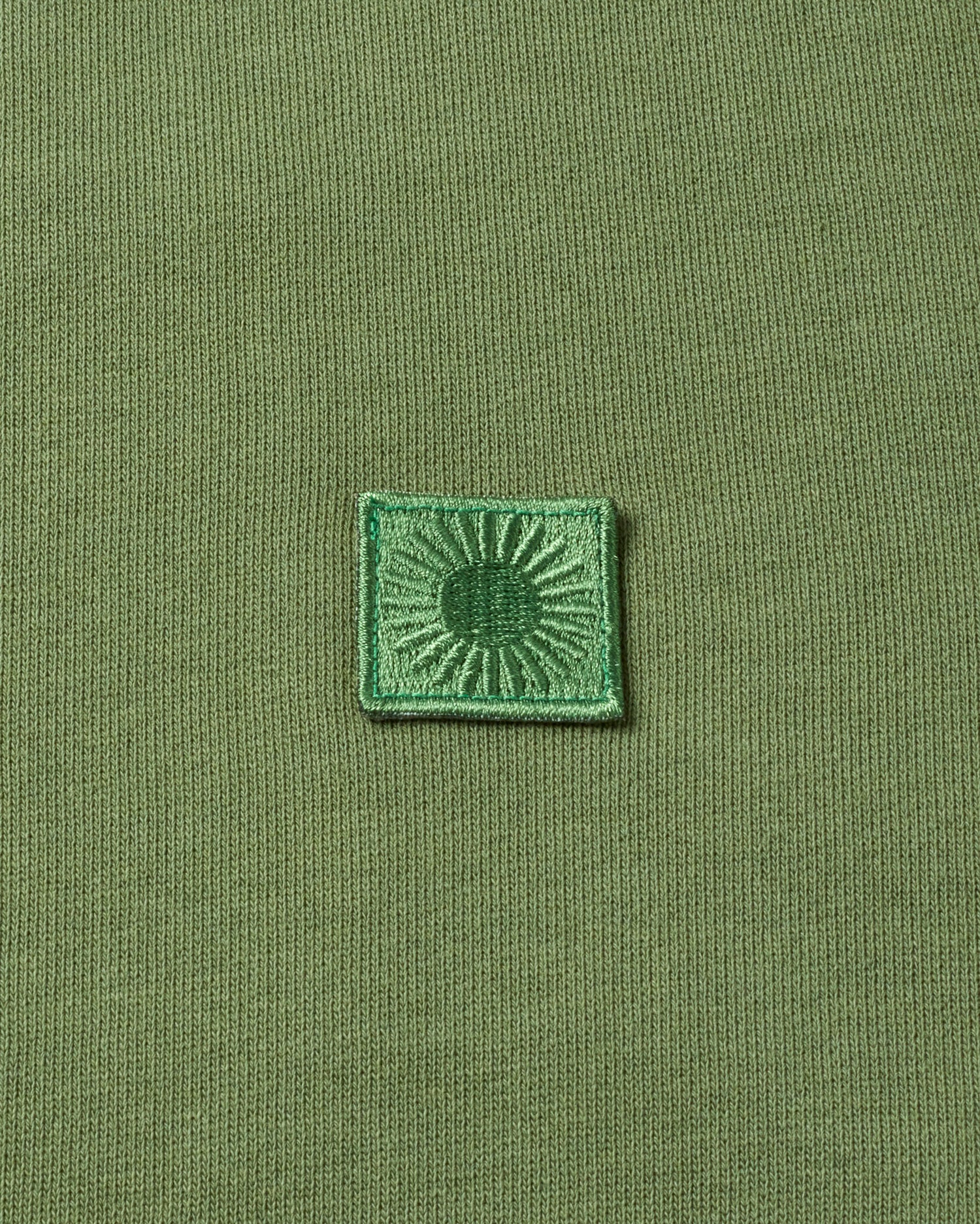 Grünes Emblem auf gestricktem Stoff.