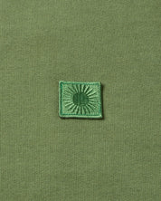 Grünes Emblem auf gestricktem Stoff.
