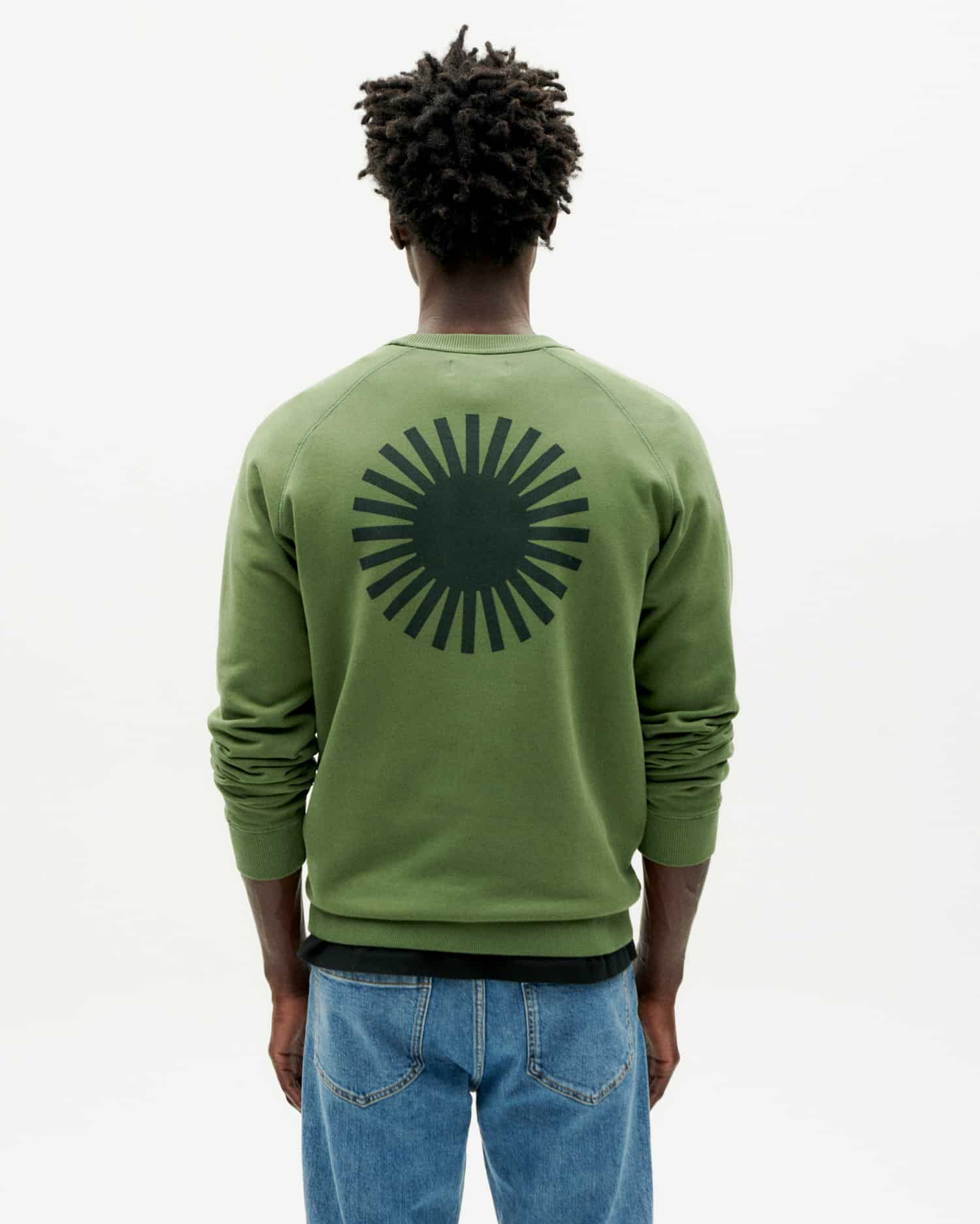 Mann trägt grünen Pullover mit Sonnenmotiv.