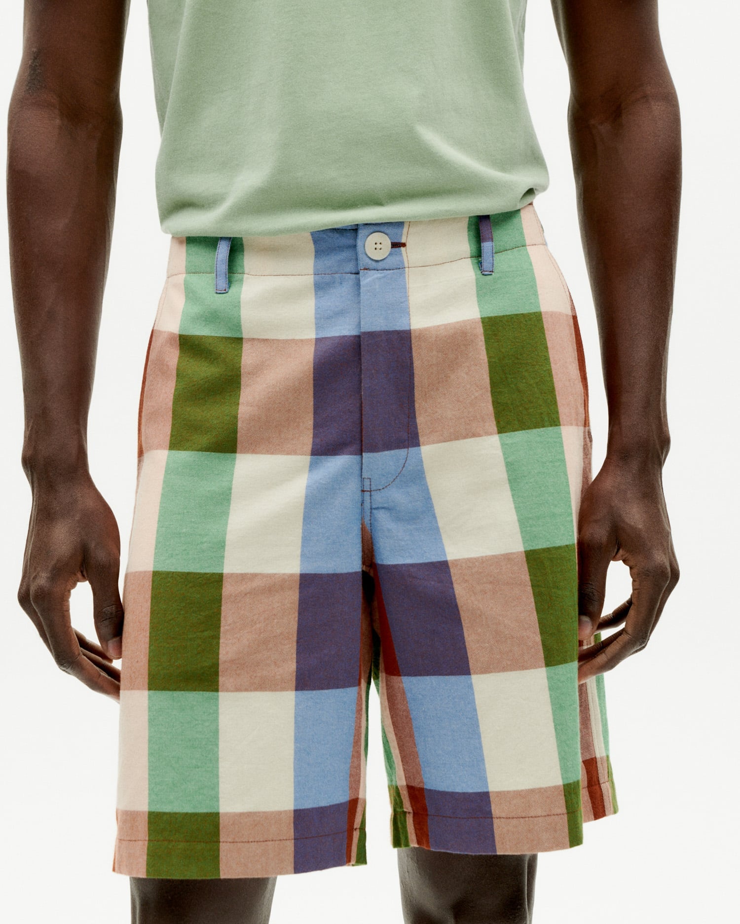 Mann trägt bunte karierte Shorts und grünes T-Shirt