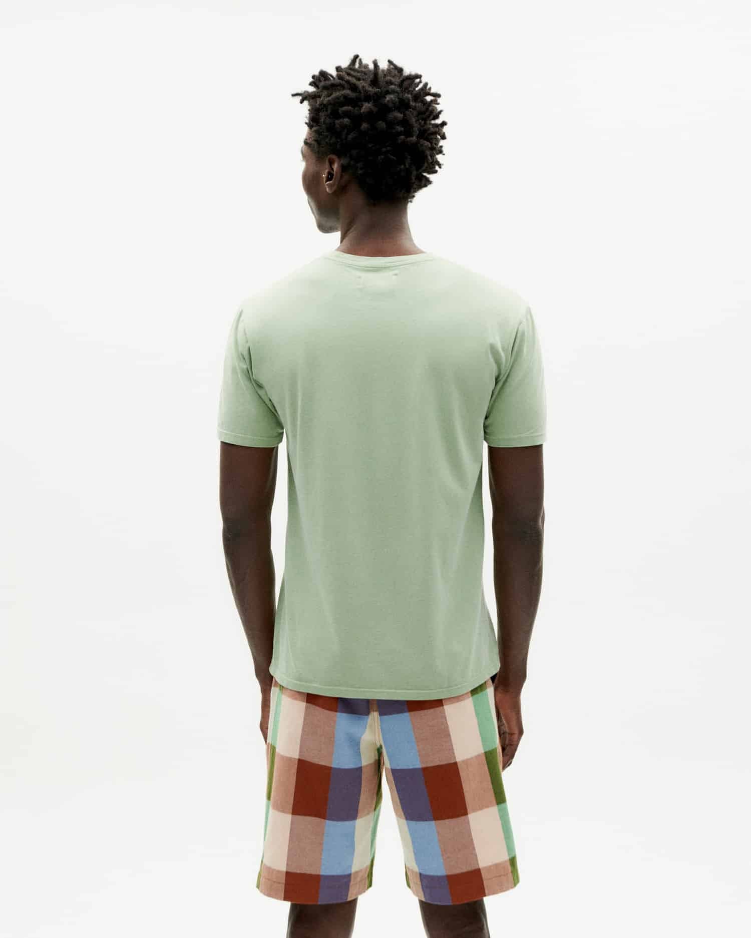 Mann von hinten mit grünem Shirt und bunter Shorts.