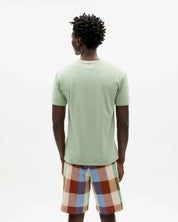 Mann von hinten mit grünem Shirt und bunter Shorts.