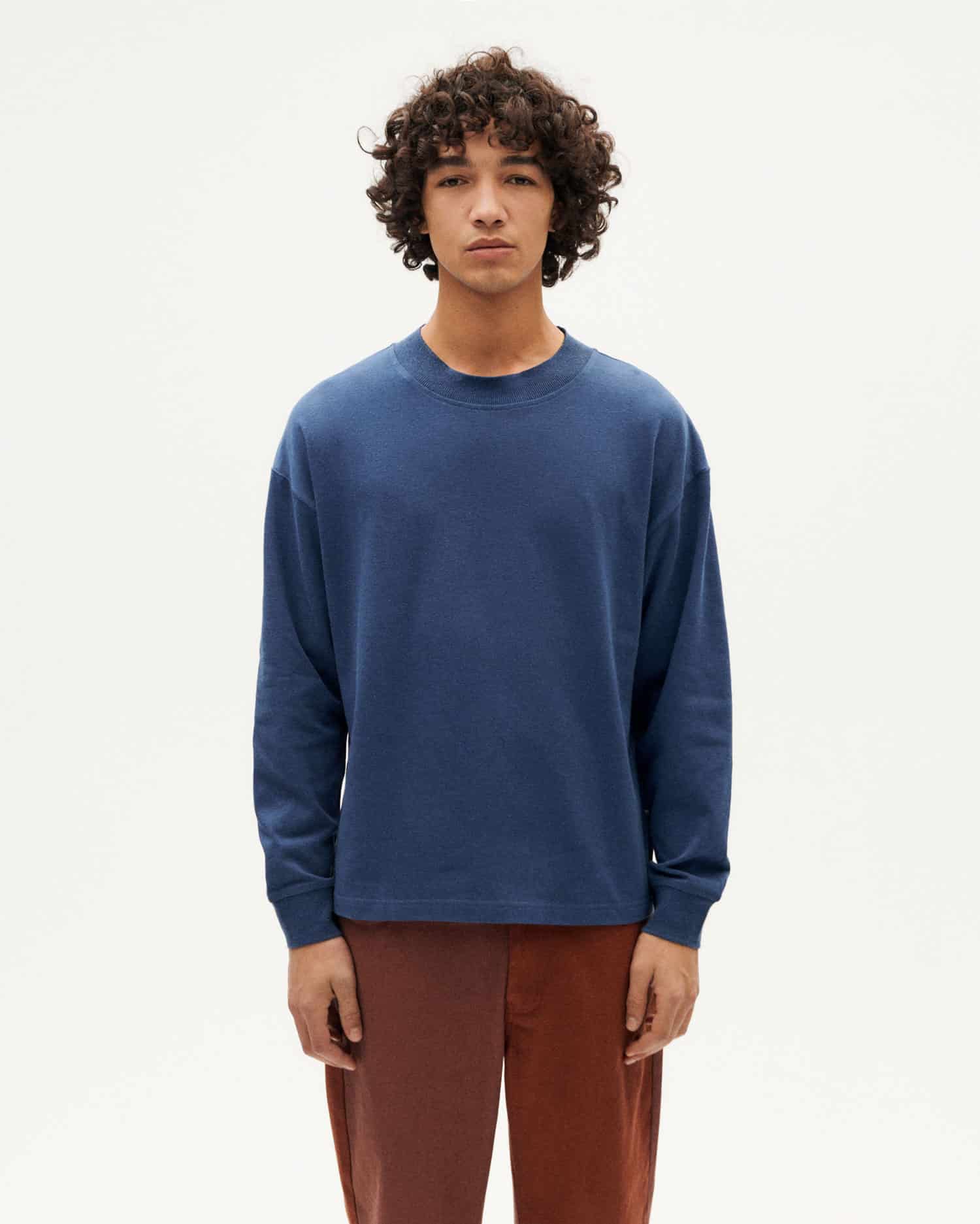 Junger Mann in blauem Pullover und brauner Hose