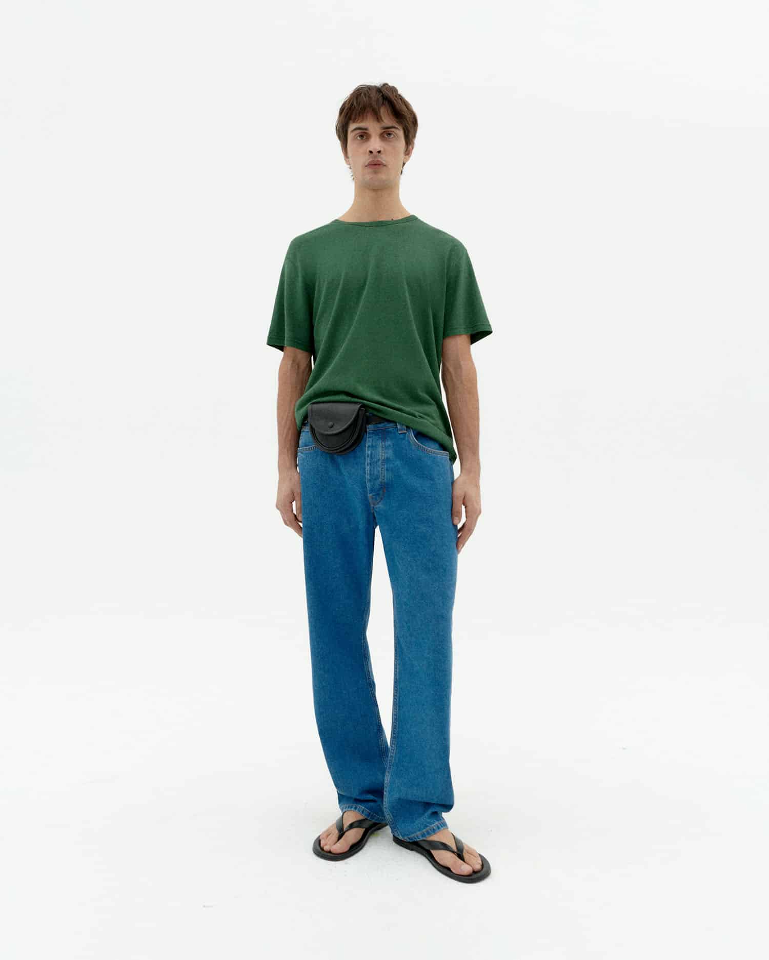 Mann in grünem Shirt und blauen Jeans steht