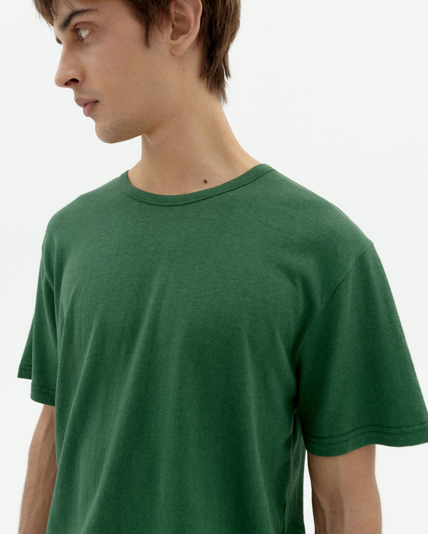 Junges Model in grünem T-Shirt seitlich