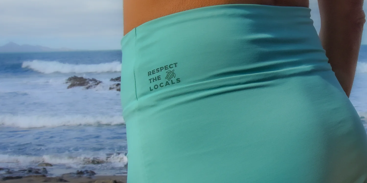 Frau in türkisem Sportoutfit am Strand.