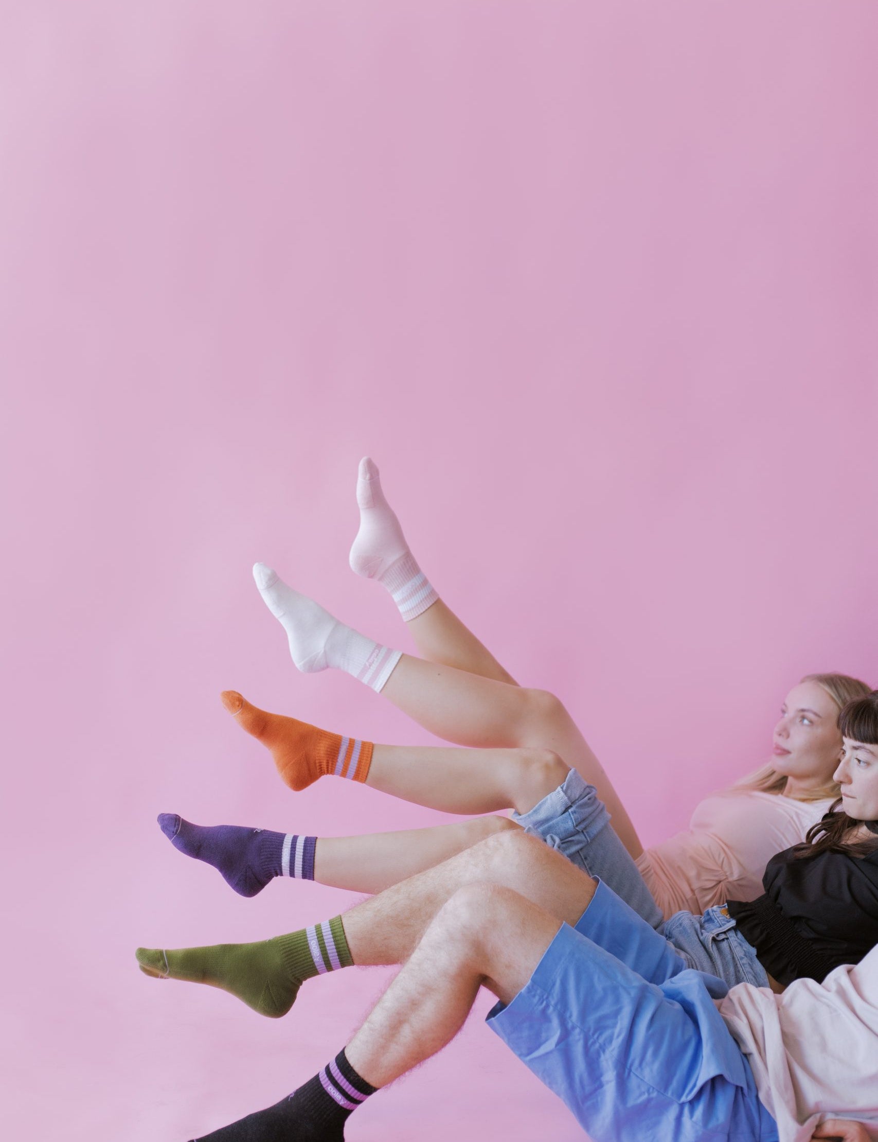 Jugendliche mit bunten Socken vor rosa Hintergrund