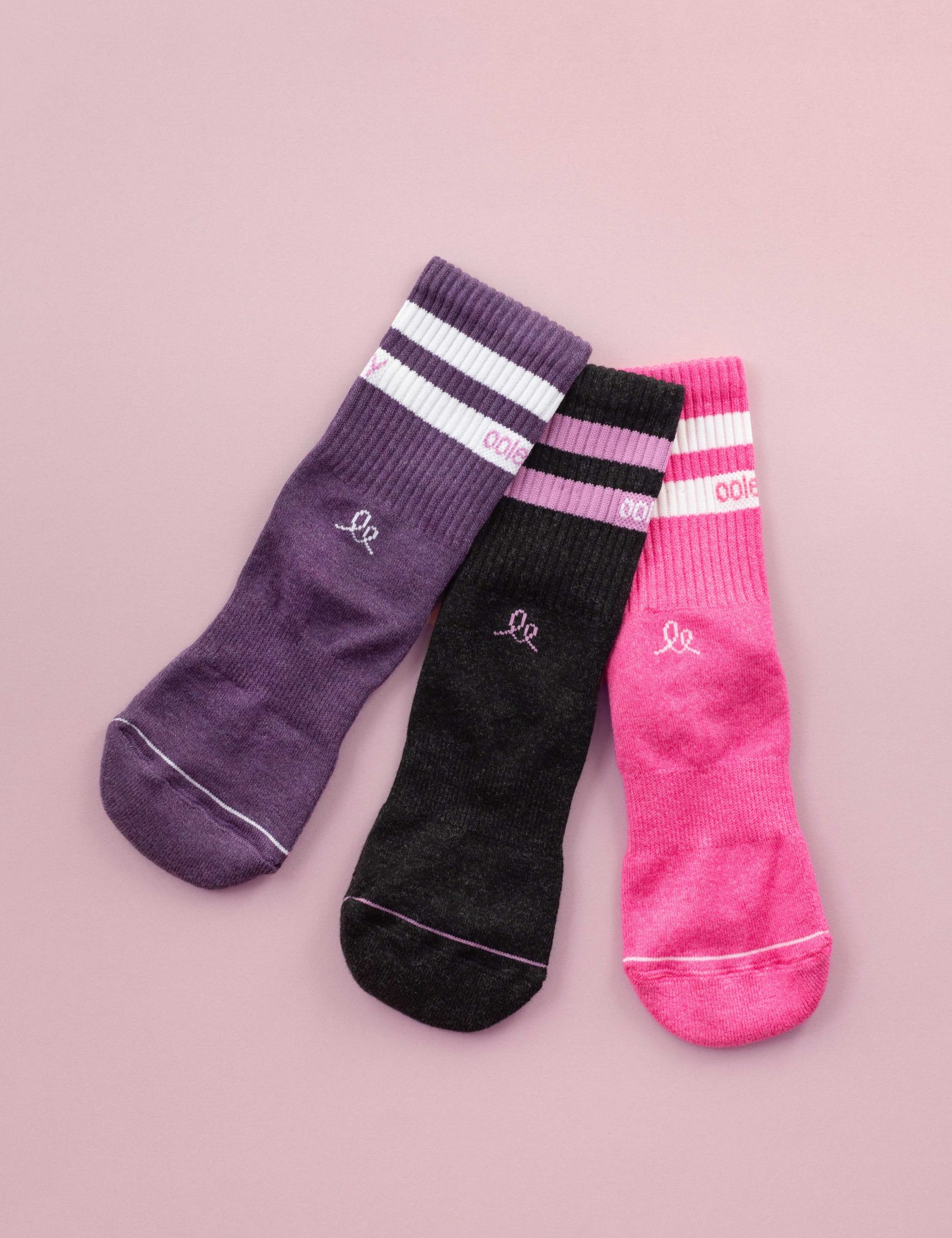 Drei farbige Kinderstrümpfe auf rosa Hintergrund