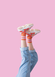 Beine in Jeans und bunten Sneakern auf rosa Hintergrund