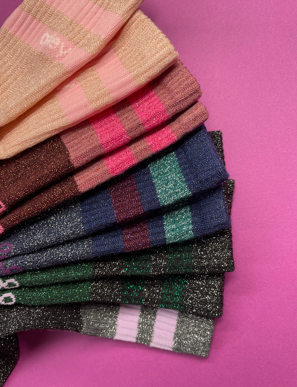 Stapel bunter glitzernder Socken auf pinkem Hintergrund