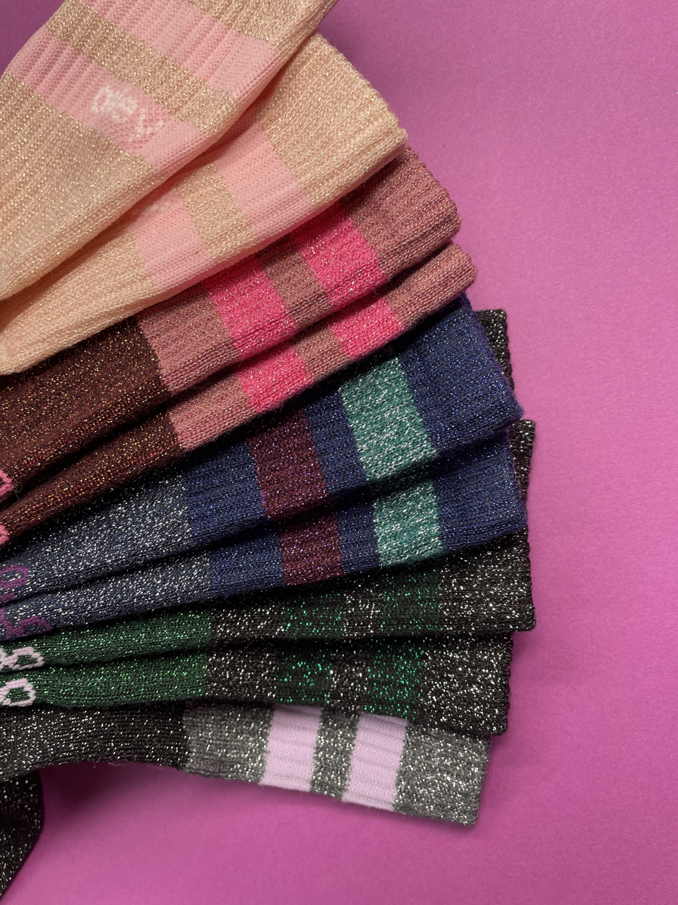 Stapel bunter glitzernder Socken auf pinkem Hintergrund