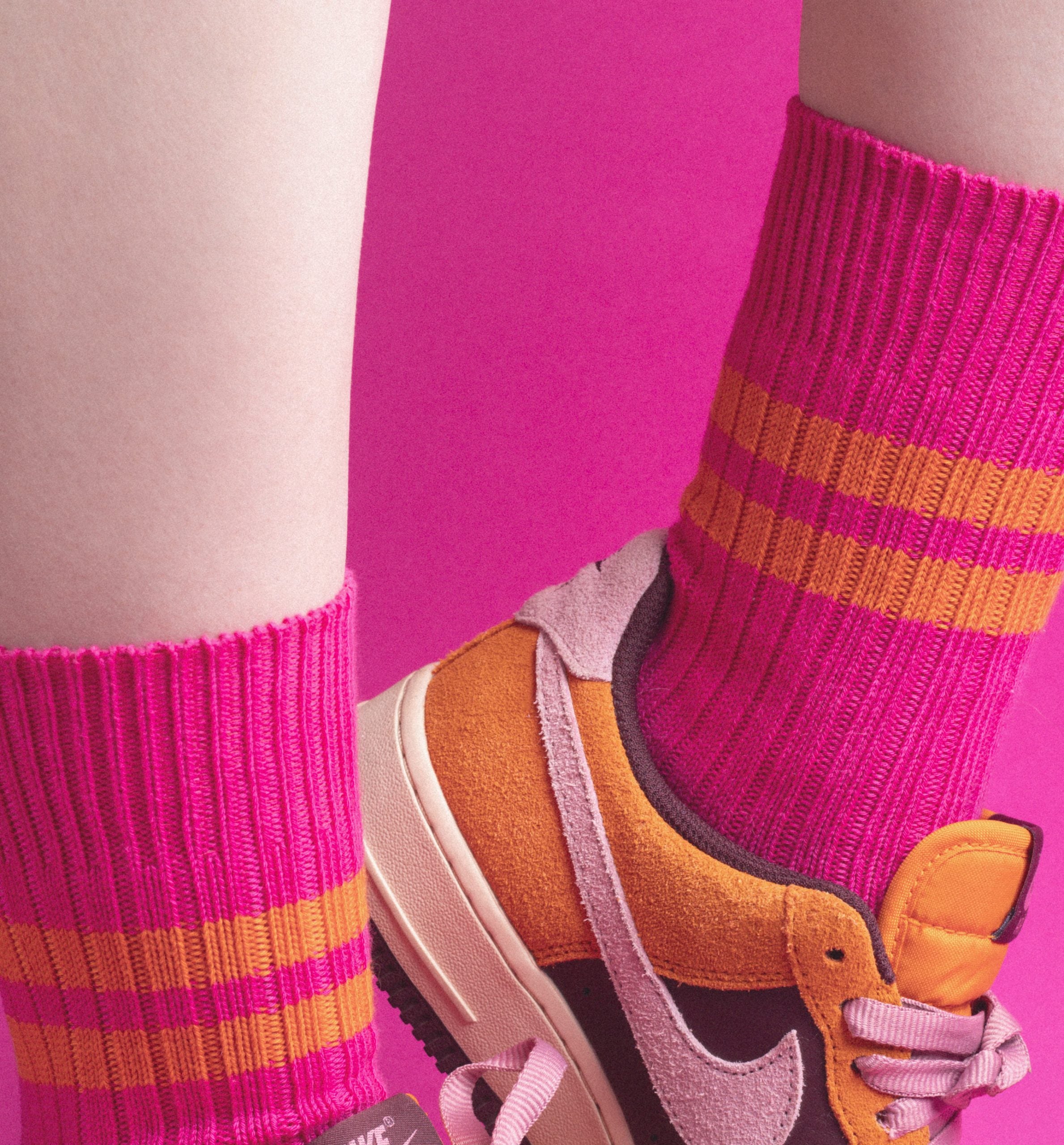 Bunte Socken und Sportschuh vor pinkem Hintergrund