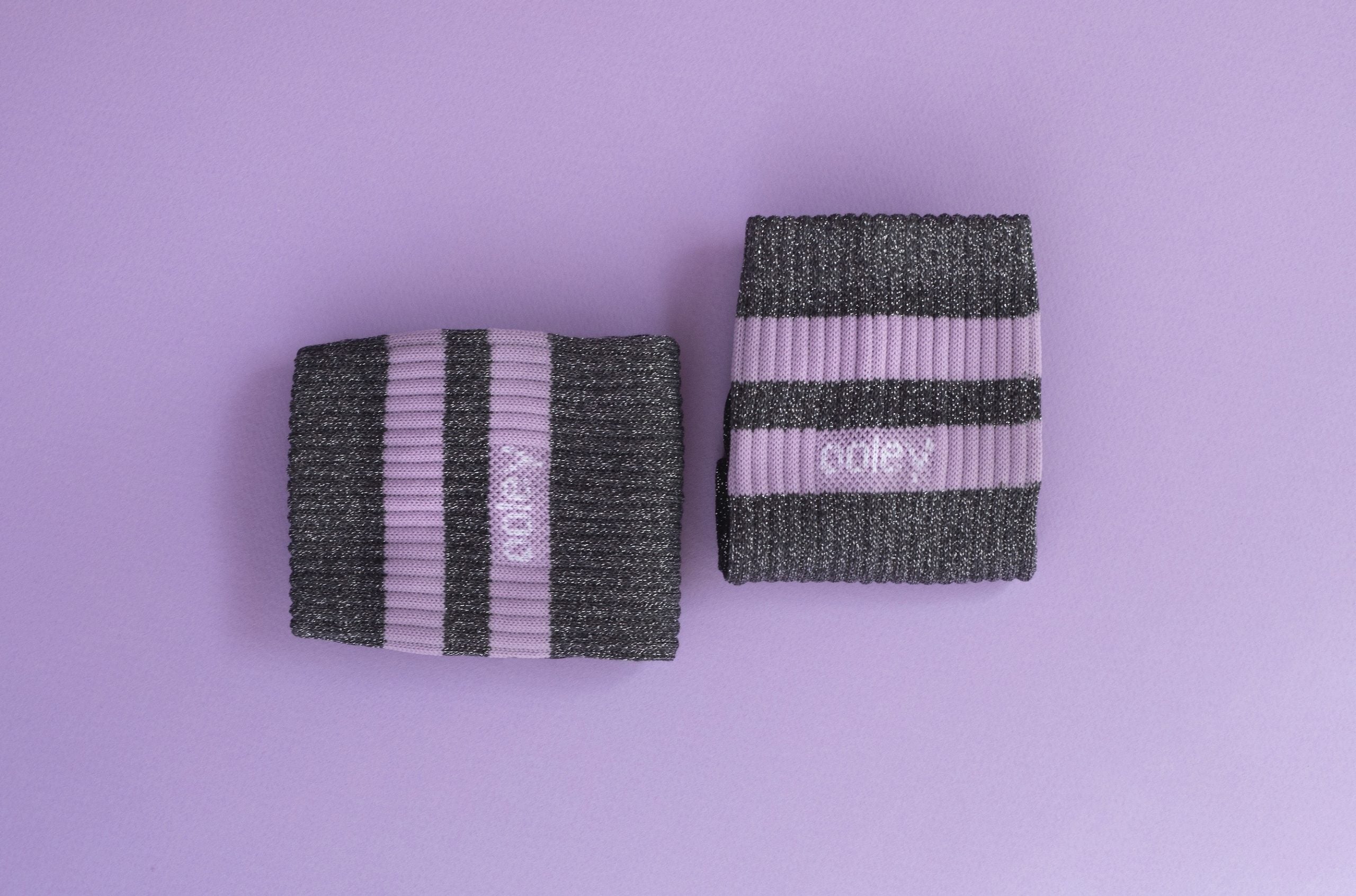 Zwei Handgelenk-Stützbandagen auf lila Hintergrund