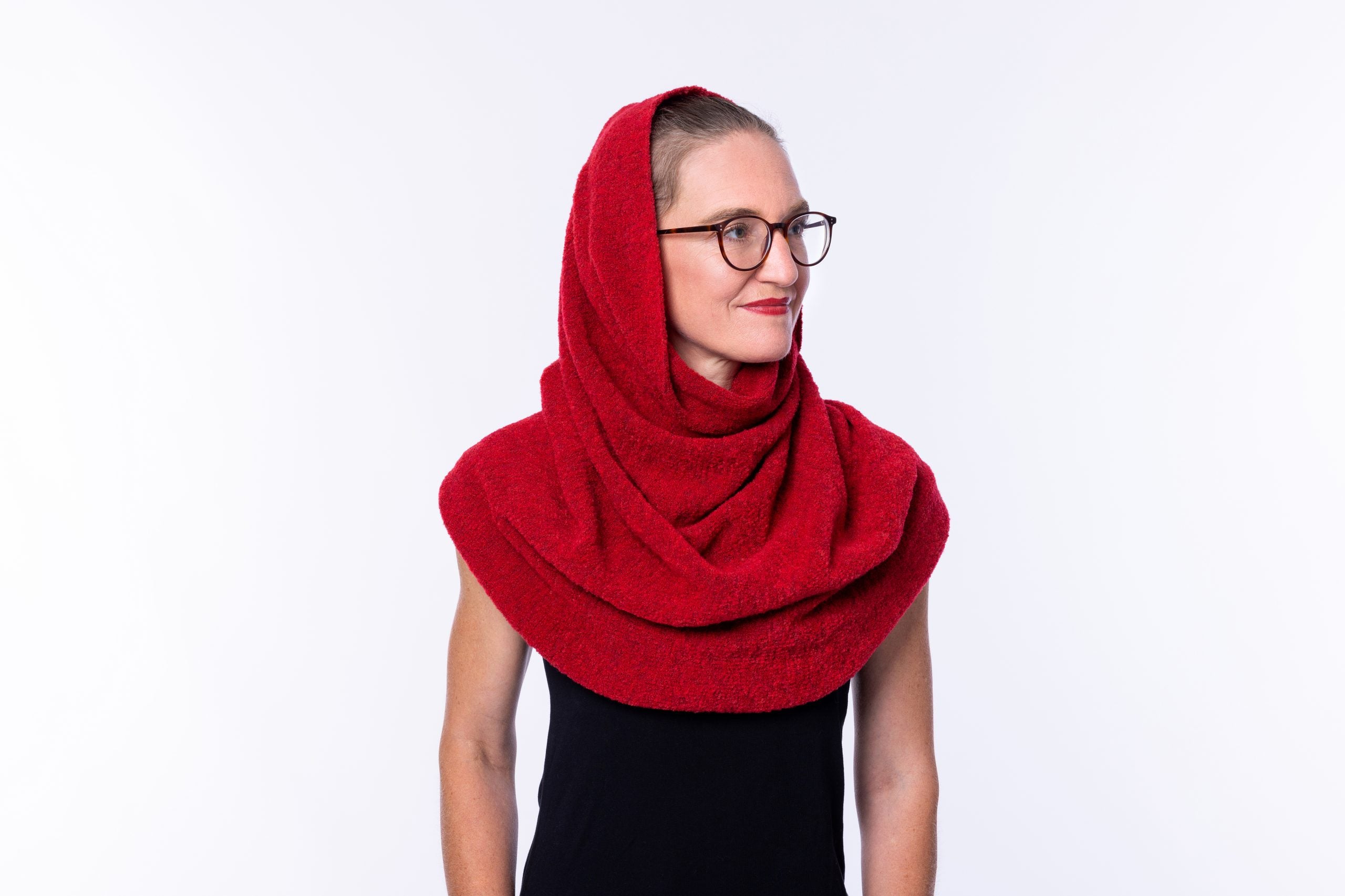 Frau mit rotem Schal und Brille lächelt seitlich