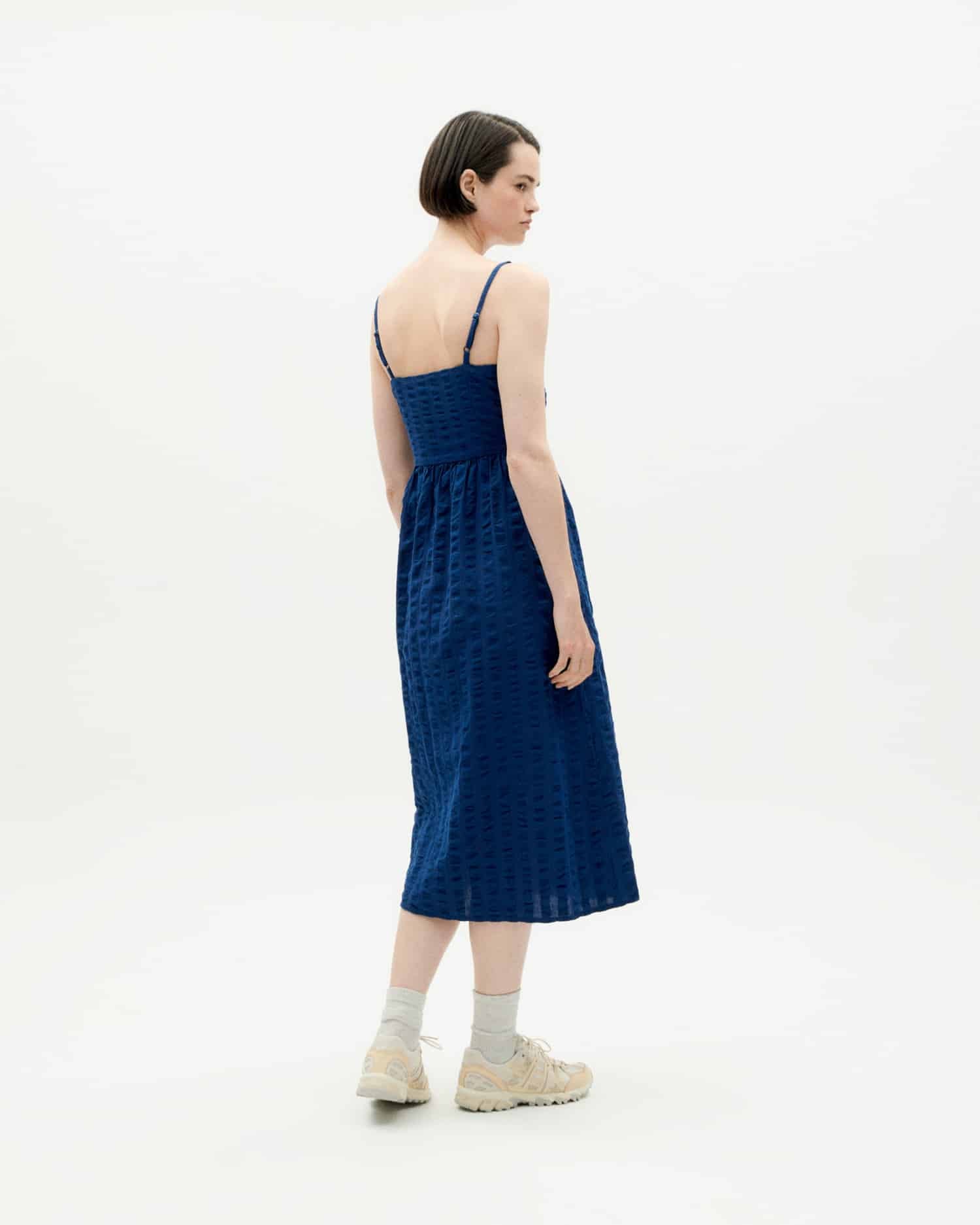 Frau in blauem Kleid von hinten betrachtet.