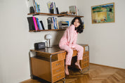 Junge Frau sitzt auf Vintage-Schreibtisch in Pyjama