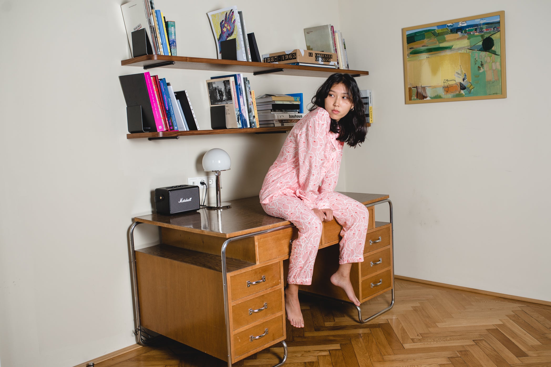 Junge Frau sitzt auf Vintage-Schreibtisch in Pyjama