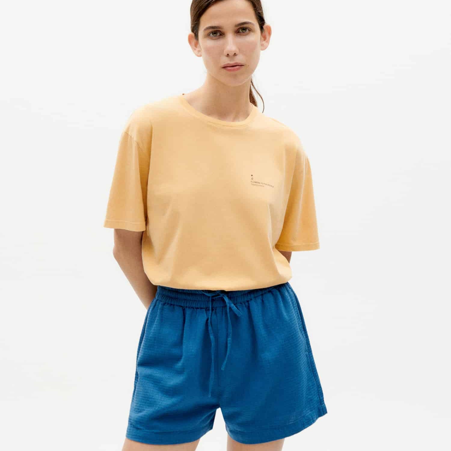 Frau in gelbem T-Shirt und blauer Shorts posiert.