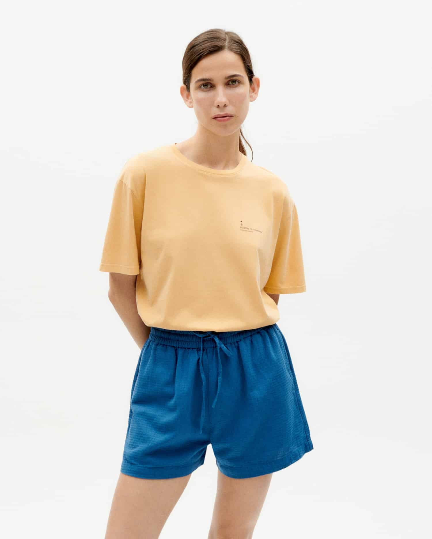 Frau in gelbem T-Shirt und blauer Shorts posiert.