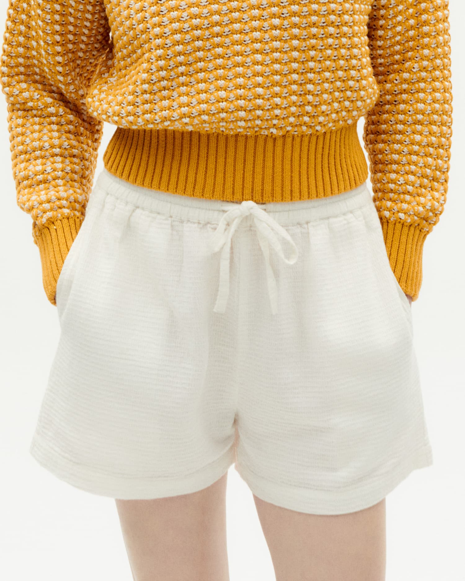 Frau in gelbem Strickpullover und weißen Shorts.