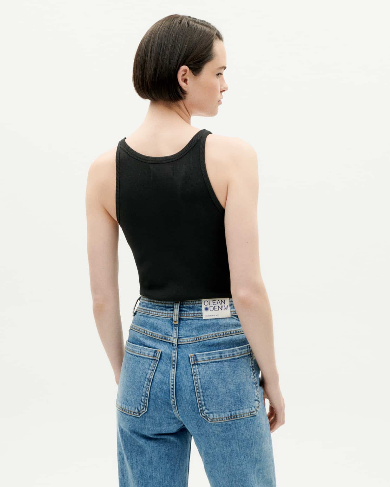 Frau in Jeans und schwarzem Top, Rückansicht.