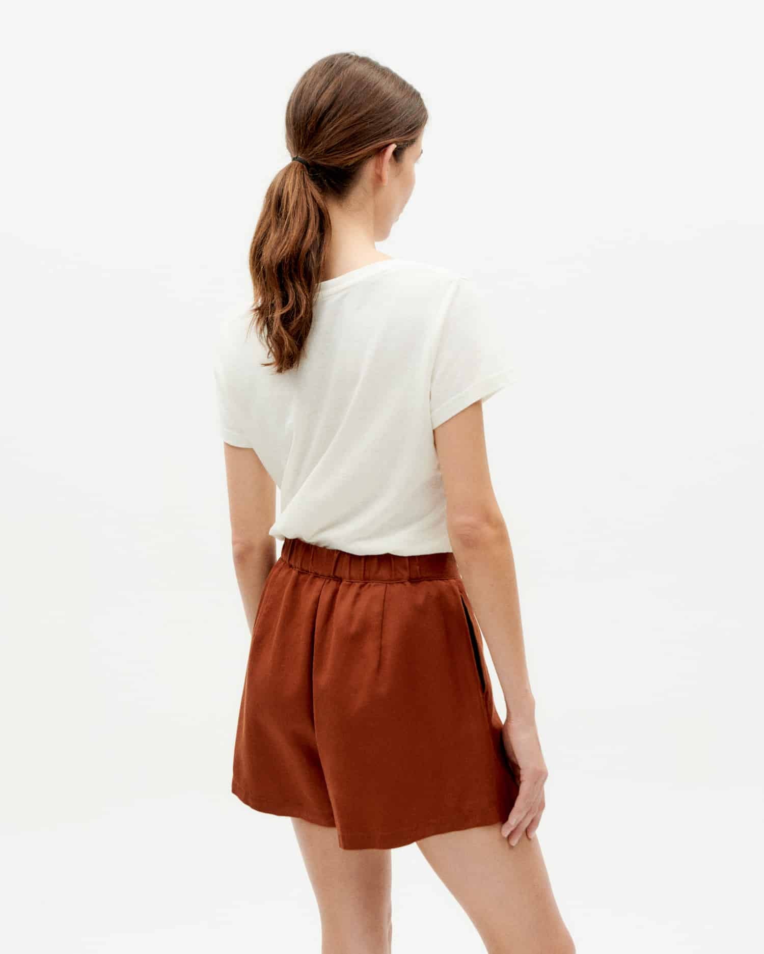 Frau in weißem T-Shirt und brauner Shorts.